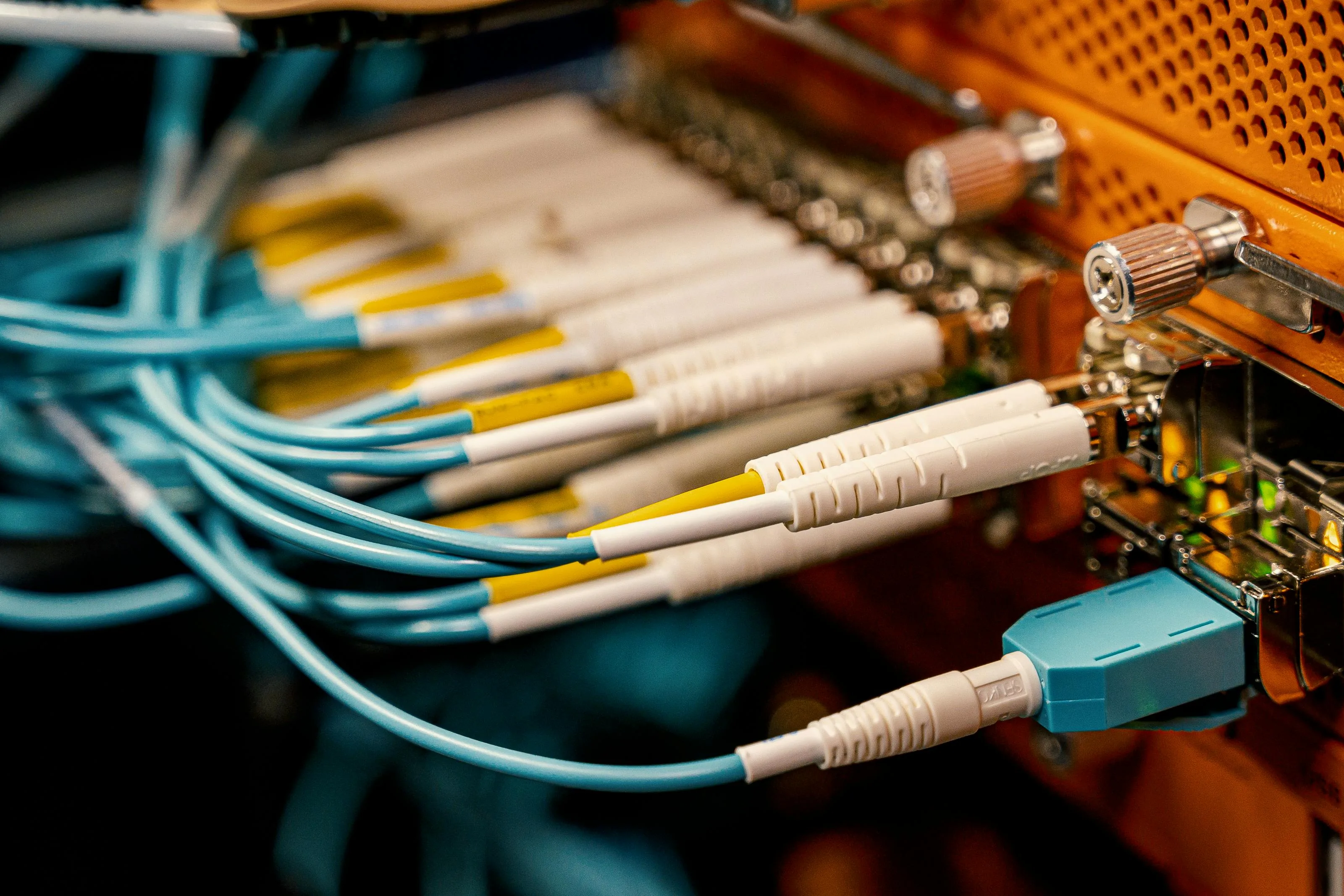 Detailed view of fiber optic cables connected to equipment in a data center. This method is used in the private network interconnection (PNI) in bilateral peering.